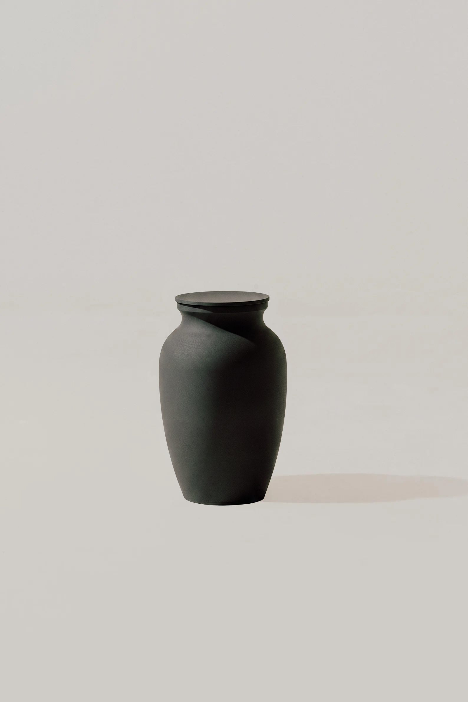 Black smooth memorial urn on a light gray background