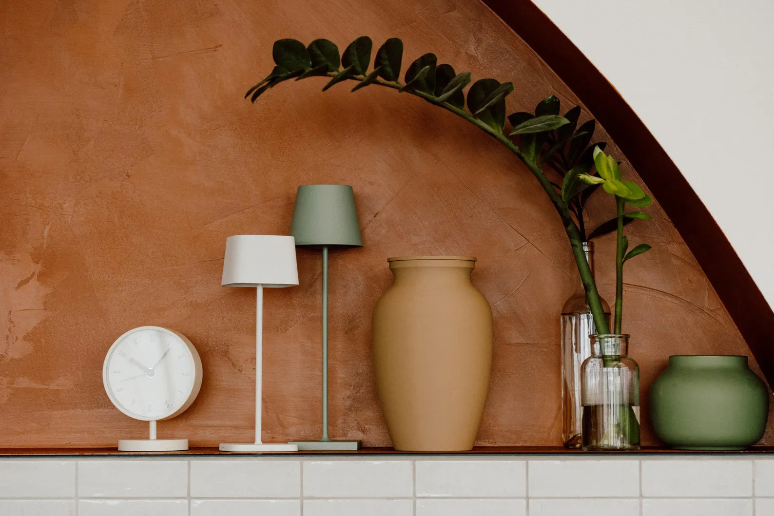 Decorative items and a brown smooth memorial urn against a brown wall.