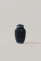 Dark blue ribbed memorial urn on a light beige background