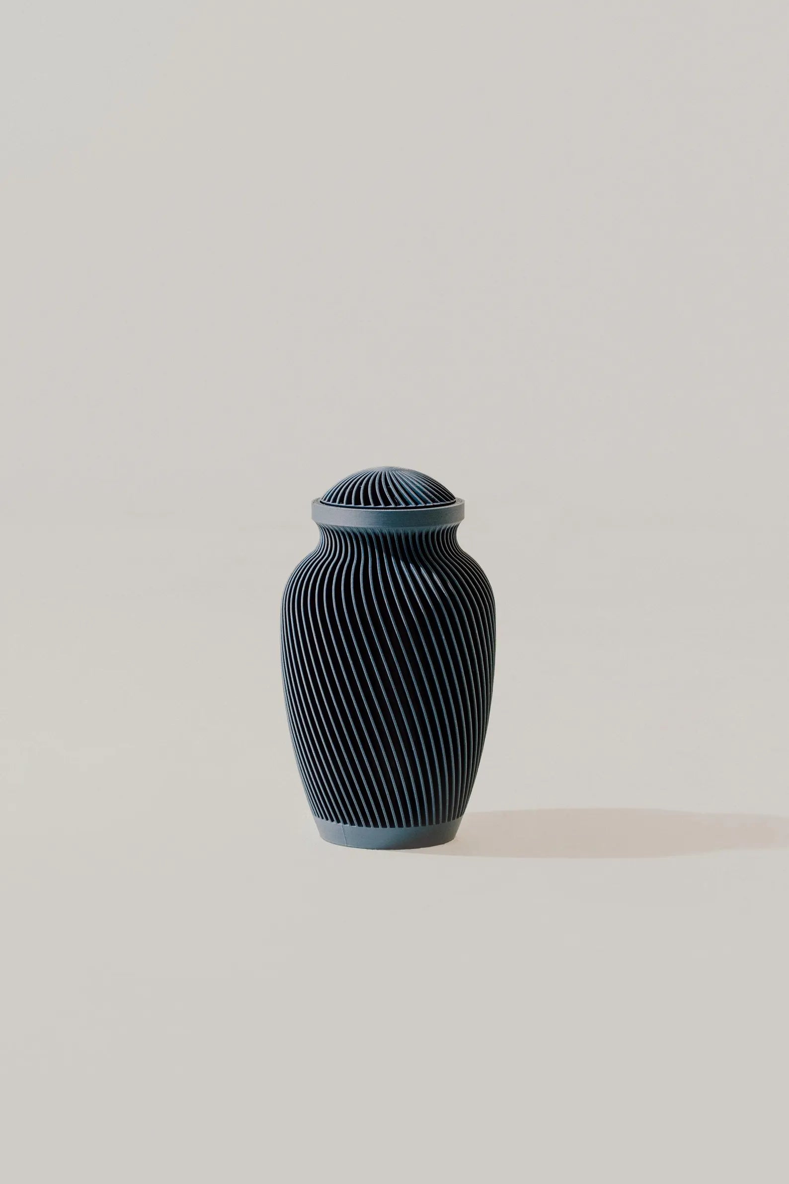 Dark blue ribbed memorial urn on a light beige background