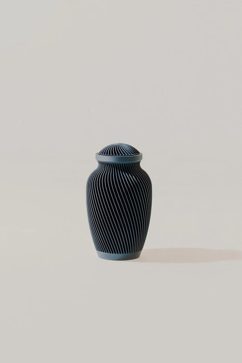 Dark blue ribbed memorial urn on a light beige background
