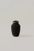 Black ribbed memorial urn on a light beige background
