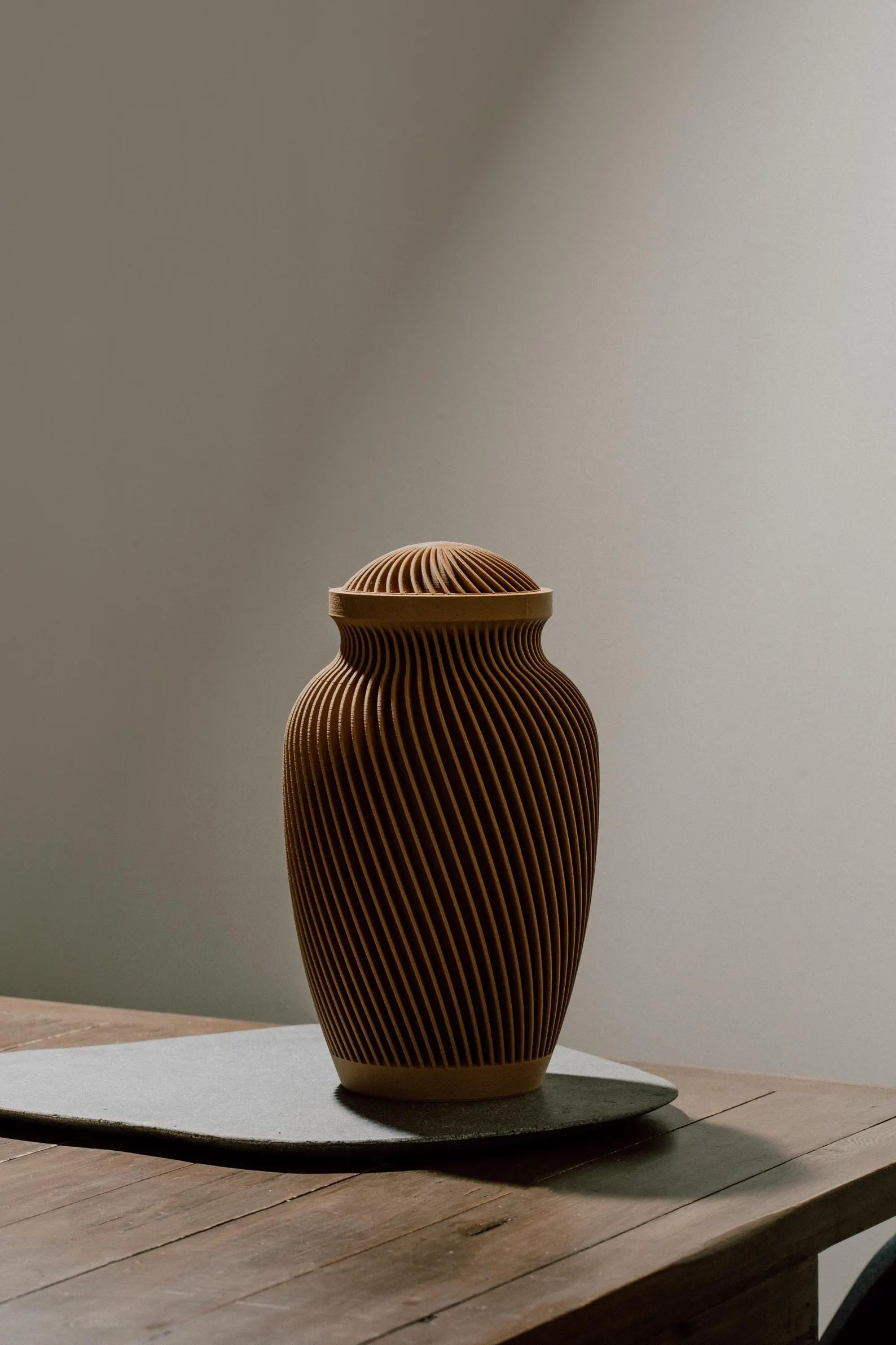 Brown textured memorial urn on a wooden table with a neutral background