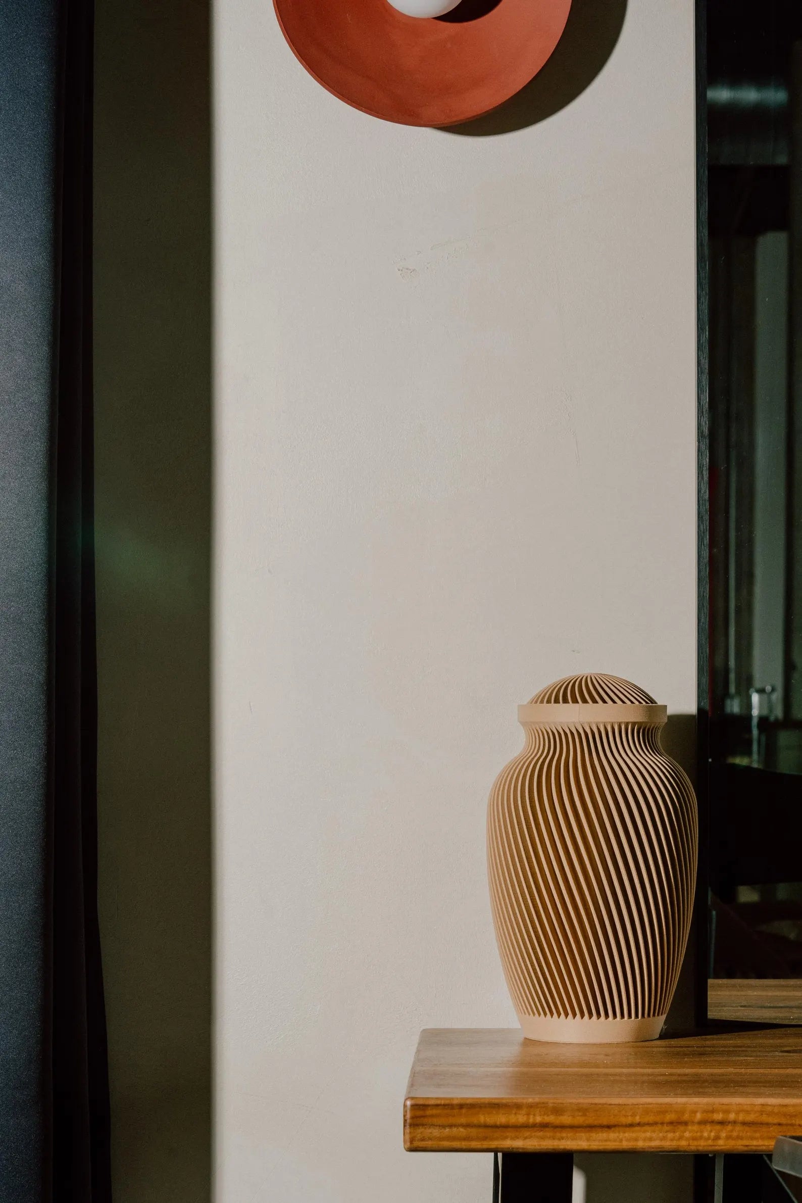 Sand Wooden memorial urn on a wooden table with a plain wall in the background