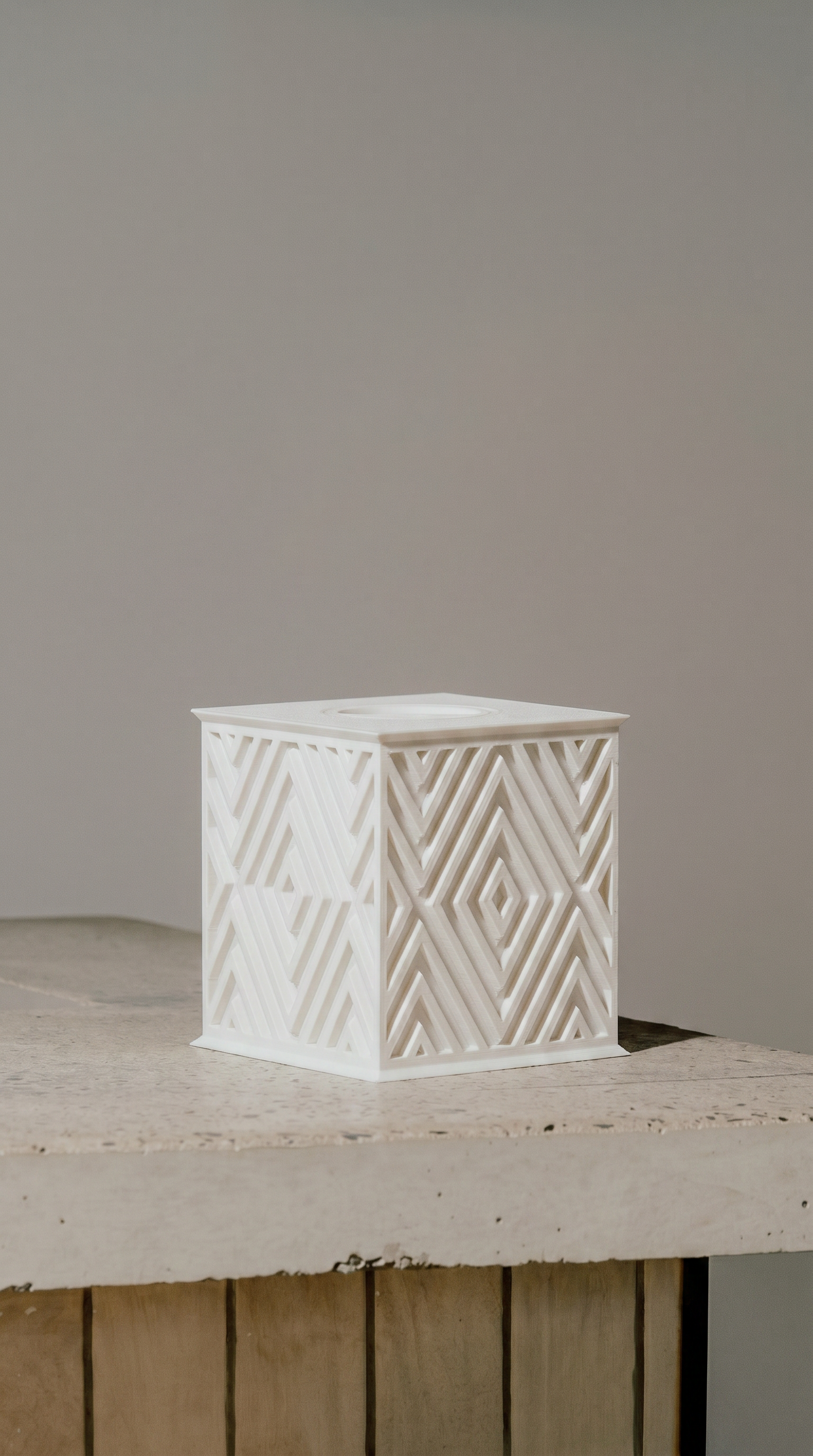 Beautiful white memorial urn with geometric pattern on a wooden surface against a plain background