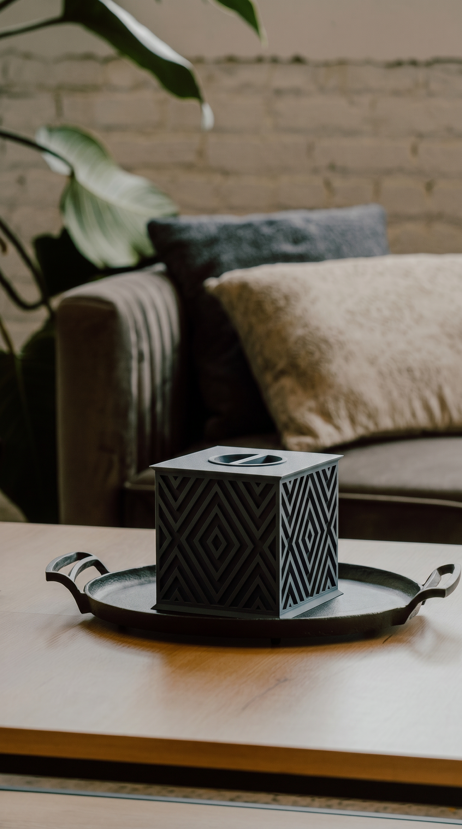 Beautiful black wood memorial urn with geometric pattern on a tray with a blurred background of a living room.