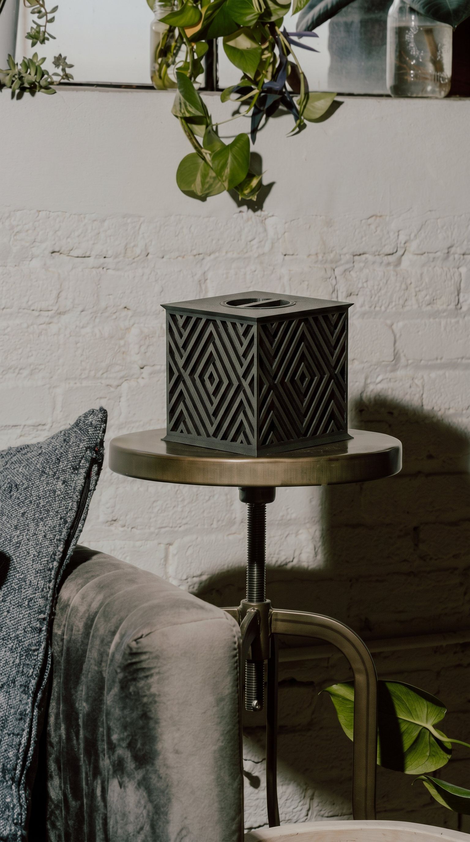 Beautiful memorial urn with geometric pattern on a small round table against a white brick wall.