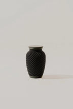 Black textured memorial urn on a light gray background