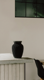 Black textured memorial urn on a wooden surface with a neutral background