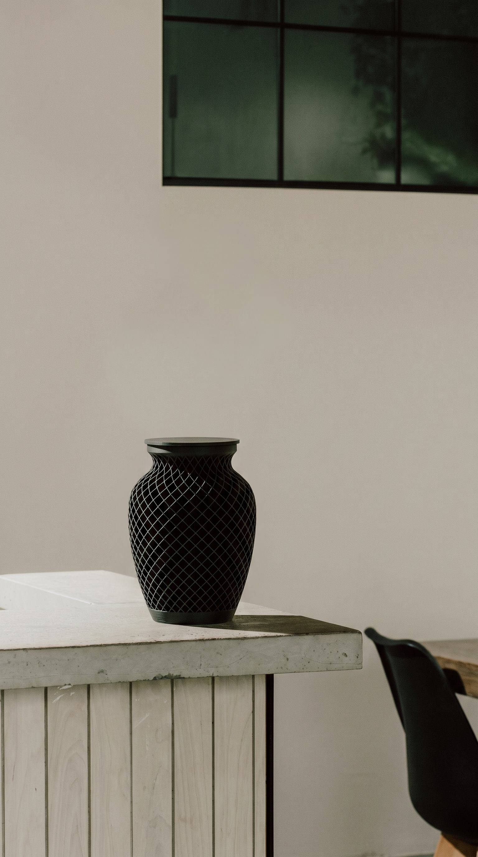 Black textured memorial urn on a wooden surface with a neutral background