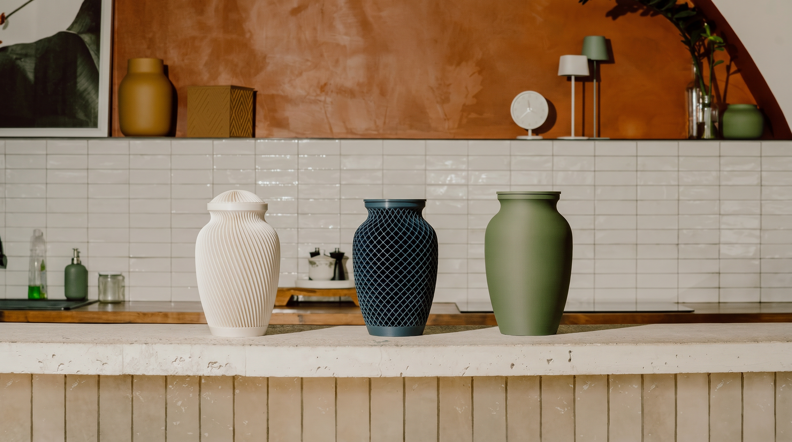 Three Elmwood Memorials urns on a kitchen counter with a tiled wall and decorative items in the background